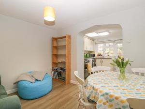 a dining room with a table and a blue ottoman at Primrose Cottage in Westbury