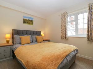 a bedroom with a large bed and two windows at Primrose Cottage in Westbury