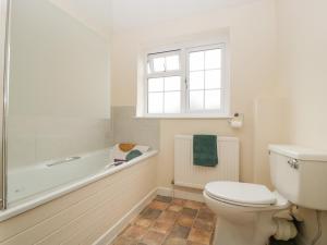 a bathroom with a toilet and a tub and a sink at Primrose Cottage in Westbury