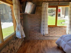 um quarto com janelas, uma cama e uma televisão em Cabaña Pampa em Esquel