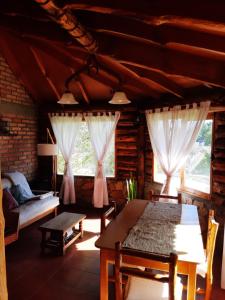 Cabaña Pampa في إيسكيل: غرفة معيشة مع طاولة وكراسي ونوافذ