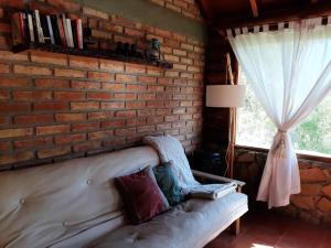 ceglana ściana z kanapą w pokoju z oknem w obiekcie Cabaña Pampa w mieście Esquel