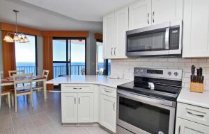 a kitchen with white cabinets and a microwave and a table at Phoenix X 1208 in Orange Beach