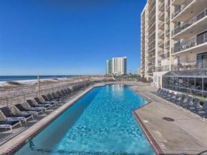 a swimming pool next to a beach with chairs and a building at Phoenix X 1208 in Orange Beach