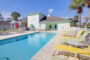 a swimming pool with yellow chairs and a house at Orange Beach Villas - Casa Bella in Orange Beach