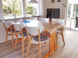 einen Esstisch mit weißen Stühlen und einen TV in der Unterkunft Holiday Home Dane - 500m from the sea in Western Jutland by Interhome in Blåvand