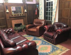 a living room with leather furniture and a fireplace at Lyttleton Lodge in Uxbridge