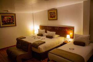 a hotel room with two beds and a chair at Hotel Retama Machupicchu in Machu Picchu