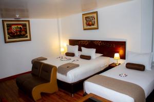 a hotel room with two beds and a chair at Hotel Retama Machupicchu in Machu Picchu