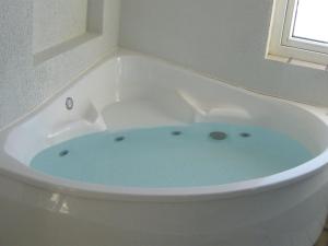 La salle de bains est pourvue d'une baignoire blanche avec de l'eau bleue. dans l'établissement Holiday Home Gunny - 500m to the inlet in Western Jutland by Interhome, à Blåvand