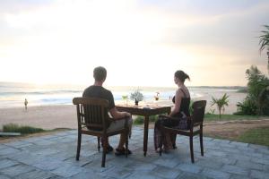 a man and woman sitting at a table near the beach at The Beach Cabanas Retreat & Spa in Koggala