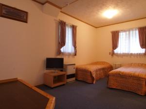 a hotel room with two beds and a flat screen tv at Pension Ciel in Hakuba