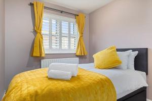a bedroom with a bed with a yellow blanket and a window at Flourish Apartments - Footbury House - Orpington in Orpington