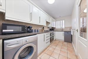 a kitchen with a washing machine and a microwave at Flourish Apartments - Footbury House - Orpington in Orpington
