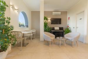 een wachtkamer met tafels en stoelen en een tv bij New Ca'Mea in Villasimius