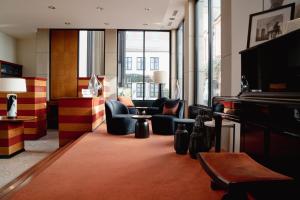 Domicil Hotel Bonn في بون: غرفة معيشة فيها بيانو وكراسي ونوافذ