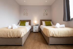 two beds sitting next to each other in a room at James Charles Apartments in Milton Keynes