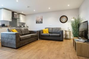 a living room with two couches and a tv at James Charles Apartments in Milton Keynes