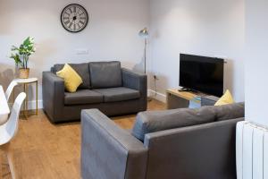 a living room with a couch and a tv at James Charles Apartments in Bletchley