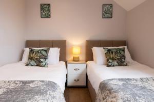two twin beds in a room with a lamp at James Charles Apartments in Bletchley