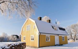 ティダホルムにあるStunning Home In Tidaholm With 4 Bedrooms And Wifiの屋根に雪が積もった黄色い家