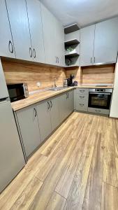 een keuken met witte kasten en een houten vloer bij Gondola Apartments Lux in Bansko