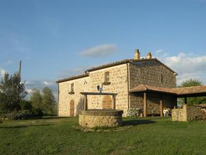 un gran edificio de piedra con una chimenea de piedra delante de él en Podere Poggio Lupinaio, en San Martino