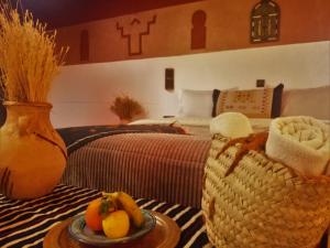um quarto com uma cama e uma mesa com um prato de fruta em Riad Bleu Afriqua em Boumalne