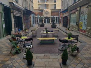 an empty street with tables and chairs in a city at Hôtel du Marché Paris in Paris