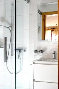 baño blanco con ducha y lavamanos en Ferienwohnung Lenk en Lenk