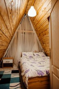 a bedroom with a bed in a wooden house at CabanaAframe intreaga proprietate in Curtea de Argeş