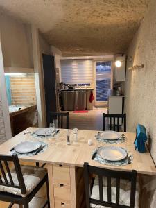 a dining table with chairs and a kitchen in the background at Troglodyte du Petit Coteau in Vouvray