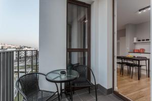 balkon ze szklanym stołem i krzesłami oraz kuchnią w obiekcie Chill Apartments Airport Ursynów w Warszawie