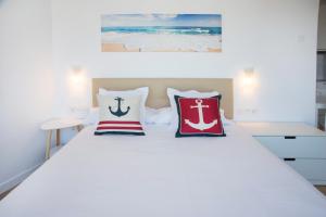 Un dormitorio con una cama blanca con almohadas. en P2 O Grove Centro con vistas al mar y parking, en O Grove