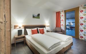 Pokój hotelowy z dużym łóżkiem z czerwonymi poduszkami w obiekcie AlpenParks Hotel & Apartment Central Zell am See w mieście Zell am See