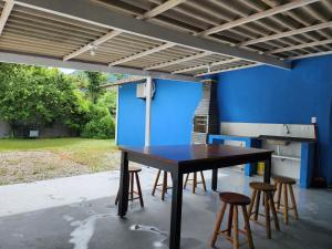 una mesa y algunos taburetes bajo una pared azul en Cantinho residencial en Maresias