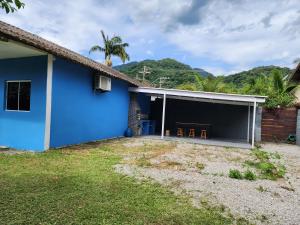 una casa blu con un ampio garage con due sedie di Cantinho residencial a Maresias