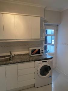 een keuken met een magnetron en een wasmachine bij Domus Santa Clara Céntrico apartamento con Wifi in León