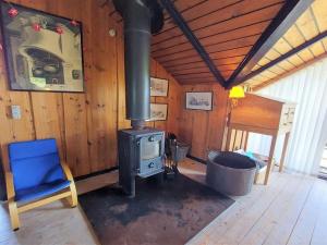 einen Holzofen in einem Zimmer mit einem blauen Stuhl in der Unterkunft Holiday Home Beneta - 300m from the sea in Western Jutland by Interhome in Hvide Sande