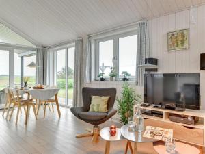 a living room with a television and a table with chairs at Holiday Home Mara - from the sea by Interhome in Ringkøbing
