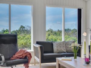 ein Wohnzimmer mit einem Sofa, einem Stuhl und Fenstern in der Unterkunft Holiday Home Alvhild - from the sea by Interhome in Ringkøbing
