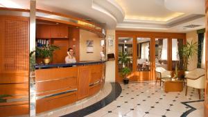 a woman standing behind a bar in a lobby at Hotel Kálvária in Győr