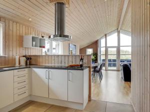 cocina con armarios blancos y comedor en Holiday Home Frido - 400m from the sea in NW Jutland by Interhome en Torsted