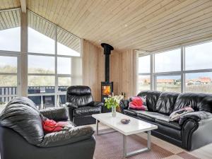 sala de estar con sofás de cuero negro y mesa en Holiday Home Frido - 400m from the sea in NW Jutland by Interhome en Torsted