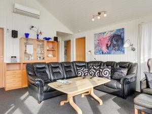 a living room with a black leather couch and a table at Holiday Home Gottfreda - 330m to the inlet in Western Jutland by Interhome in Havrvig