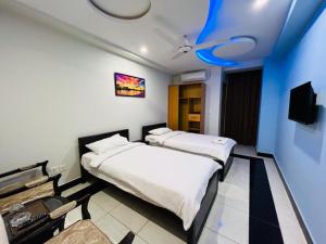 Duas camas num quarto com tecto azul em AAKAS HOTEL & RESTAURANT em Muzaffarabad