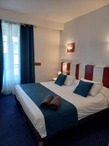 a hotel room with a large bed with blue pillows at Hôtel Le Centre in Les Herbiers