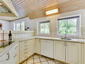 a kitchen with white cabinets and a sink and two windows at Holiday Home Thana - 1-4km from the sea by Interhome in Ulfborg +33 photos