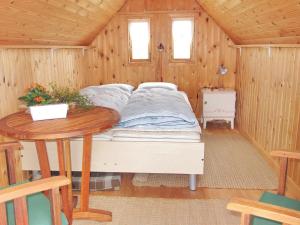 een bed in een houten kamer met een tafel bij Holiday Home Beatrice - 150m from the sea in Western Jutland by Interhome in Lemvig