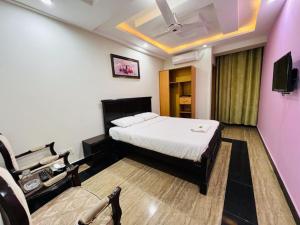 um quarto com uma cama e uma cadeira num quarto em AAKAS HOTEL & RESTAURANT em Muzaffarabad